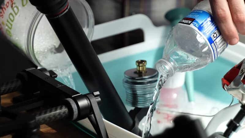Person pouring water from a bottle into studio lighting equipment during setup or maintenance.
