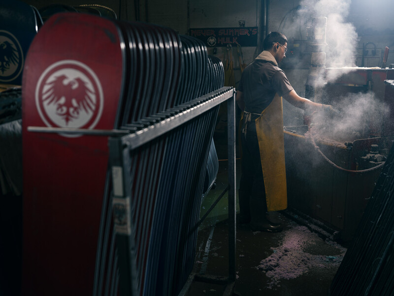 Industrial worker operating machinery with steam emission in a workshop setting.