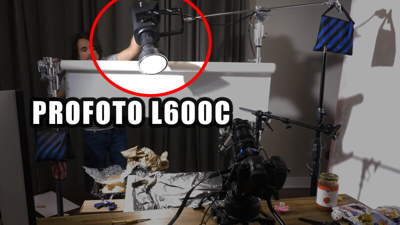 Overhead flat lay setup with Profoto L600C monolight mounted above white surface, surrounded by lighting equipment and studio accessories.