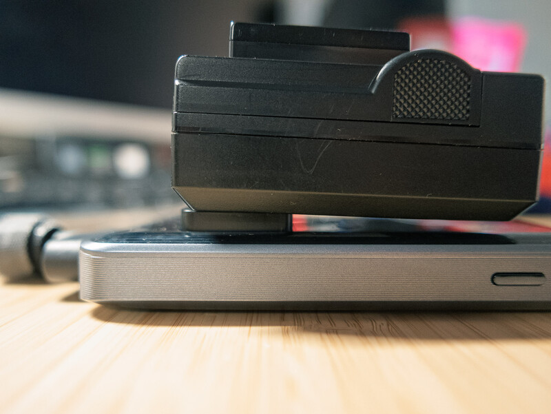 Stacked vintage instant film cameras on a smartphone, shot at eye level on a wooden surface.
