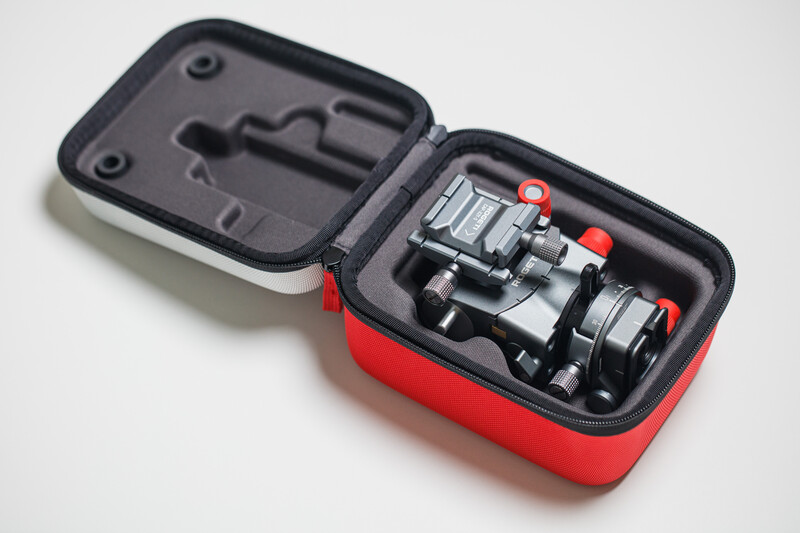 Red and black protective case with camera lens adapters and accessories inside.