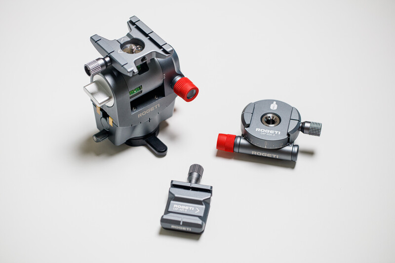 Three camera tripod heads and mounting components arranged on white background.