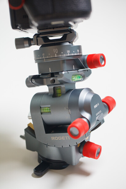 Stacked tripod head components showing ball head, geared head, and leveling base with red adjustment knobs.