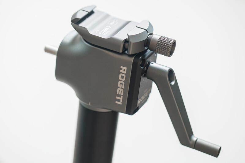 Fluid head tripod mount with gray finish and adjustable pan-tilt controls against white background.
