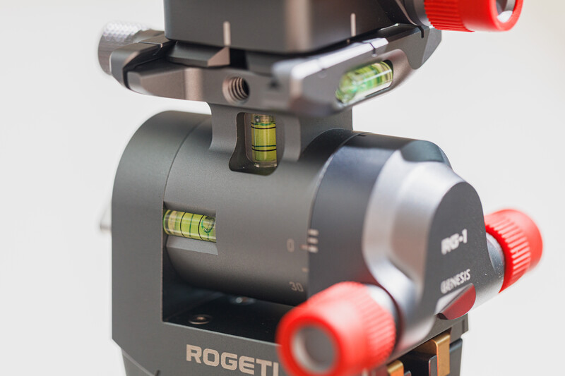 Rogeti tripod head with bubble levels and red control knobs against white background.