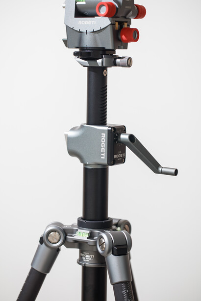 Professional tripod with fluid head and red knobs mounted on black telescoping legs against white background.