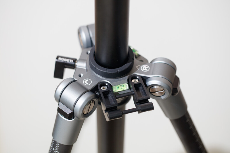 Close-up of tripod head with spirit level and pan-tilt controls mounted on dark pole.