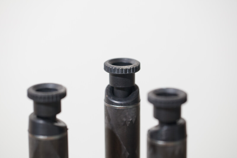 Three black lens caps or protective covers arranged in a row against a white background.