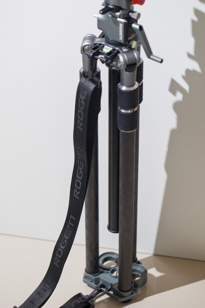 Camera tripod with black legs and extending center column against white background.