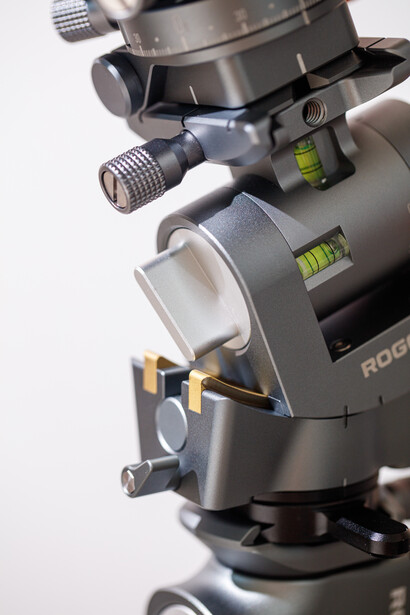 Close-up of a professional tripod head with panoramic and leveling adjustment mechanisms.