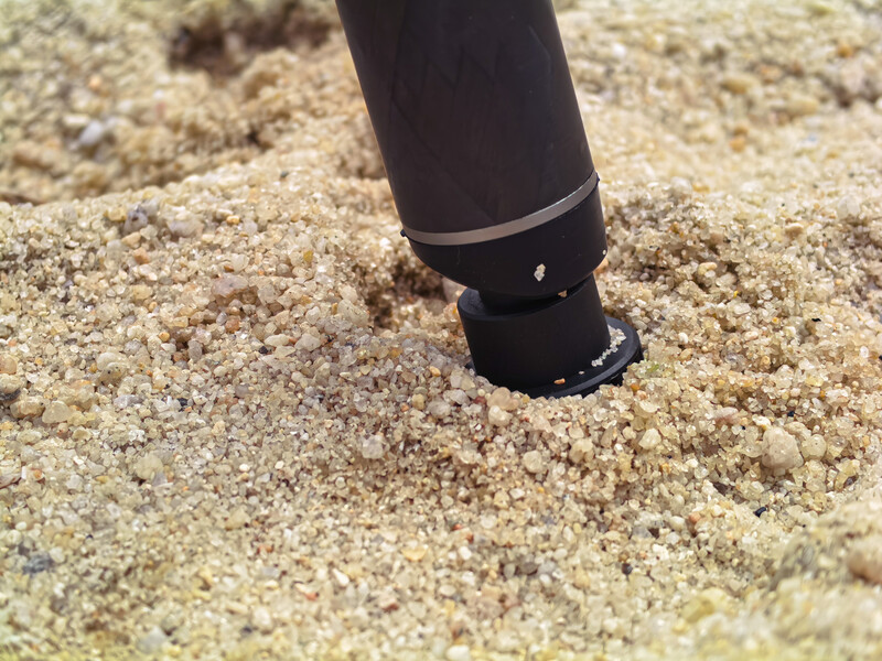 Black diving equipment positioned in sandy beach substrate during underwater photography shoot.