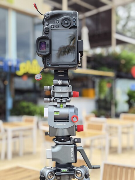 Professional camera rig with multiple mounted devices and accessories stacked vertically on tripod.