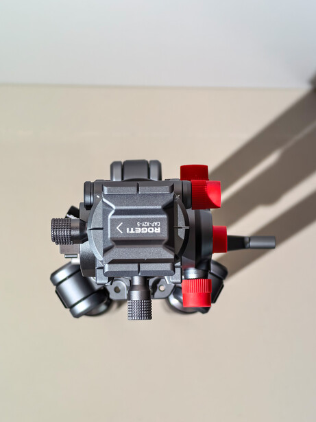 Overhead view of a compact camera flash unit with gray body and red accents on neutral background.