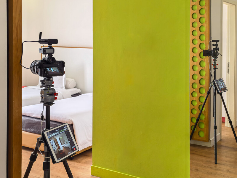 Professional camera rig with monitor mounted on tripod during bedroom product shoot setup.