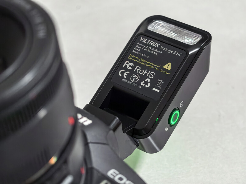 Velbon camera flash mounted on top of a DSLR camera body against a neutral background.