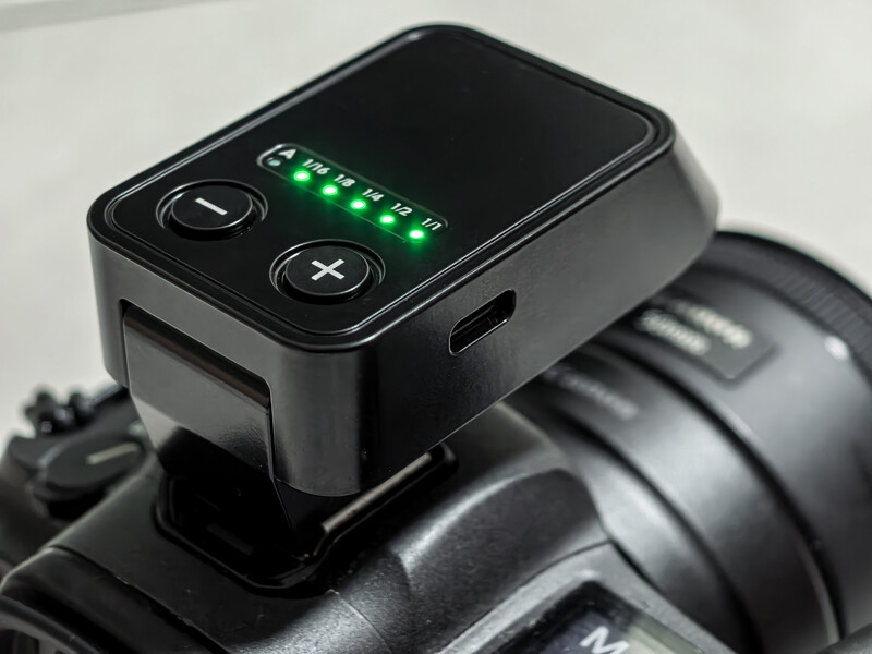 Wireless flash trigger mounted on camera hotshoe with green LED battery indicator lights illuminated.