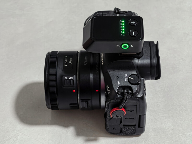 Mirrorless camera with attached zoom lens and wireless flash trigger on top plate.