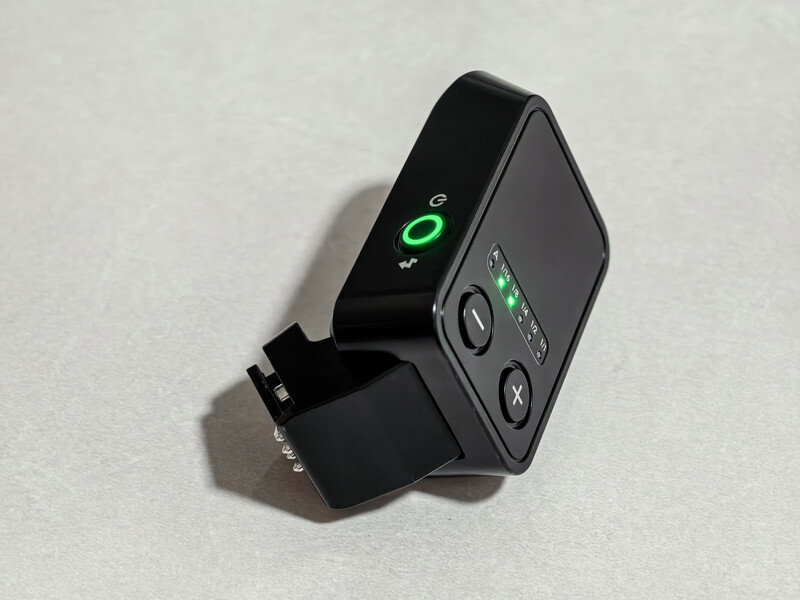 Compact wireless camera receiver with green LED indicators and a detachable antenna on a light gray surface.