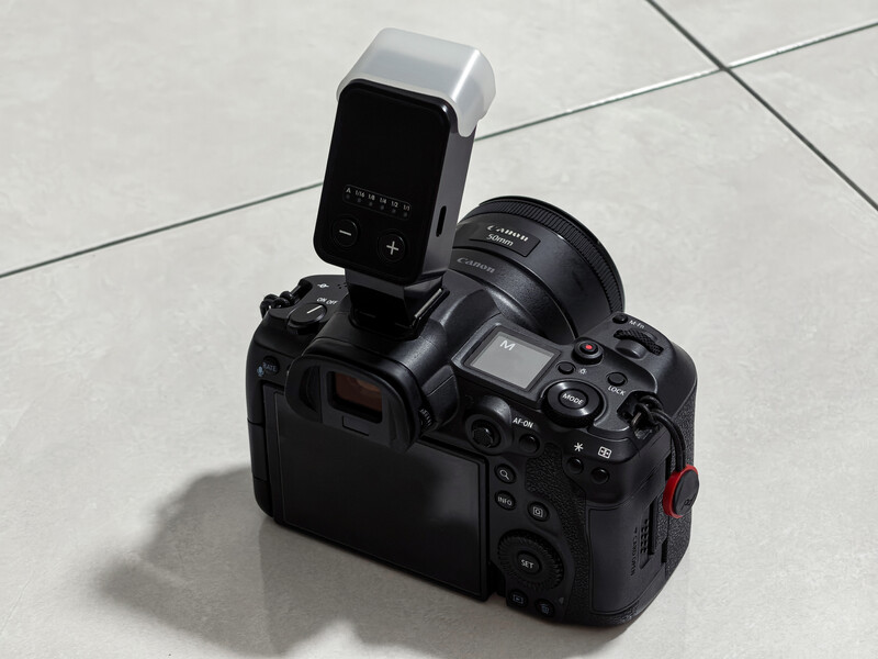 Canon DSLR camera with external flash mounted on top, photographed from above on a tiled floor.