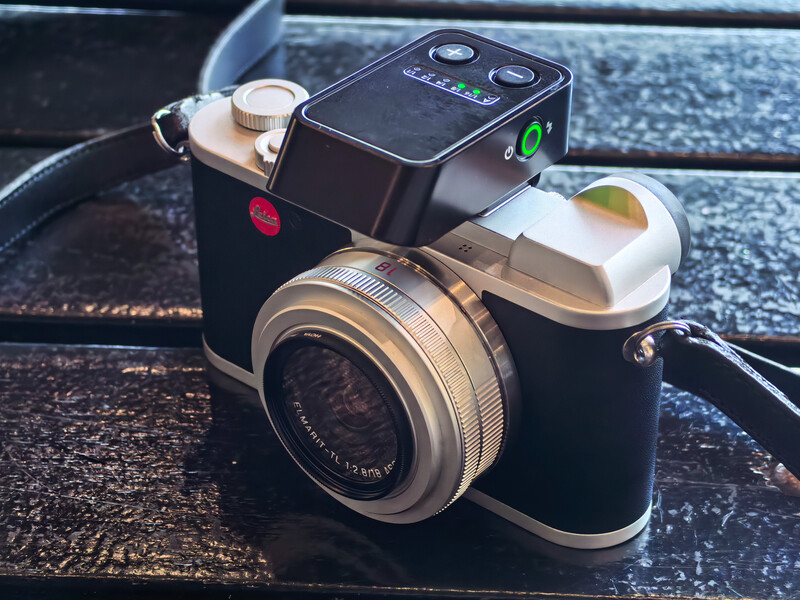 Fisheye camera with attached flash mounted on wooden surface.