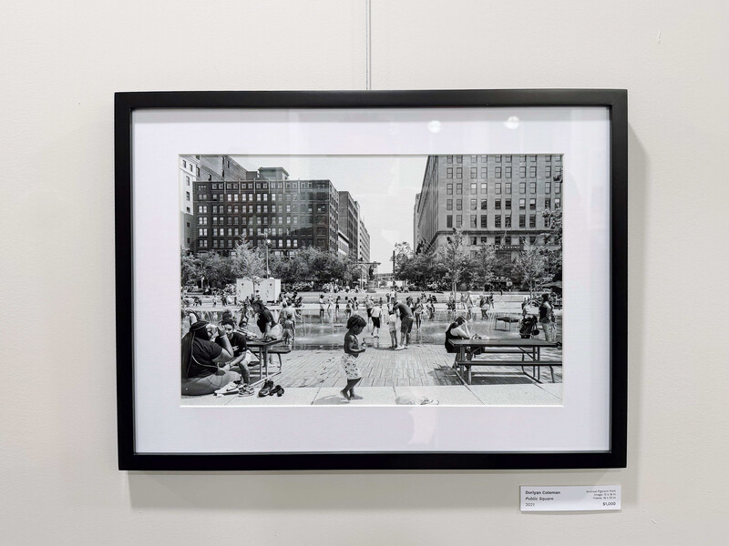Black and white photograph of a crowded urban plaza surrounded by tall buildings.