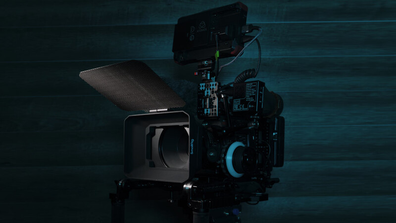 Professional cinema camera with matte box, follow focus system, and wireless monitoring equipment mounted on a darkened set.