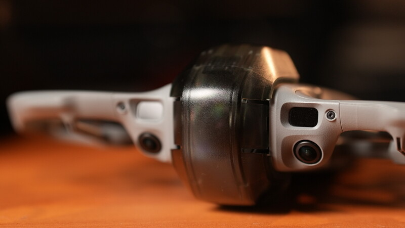 Over-ear headphones with white ear cups and black headband rest on an orange surface, shot with shallow depth of field.