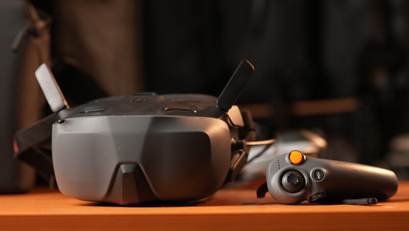 DJI Avata FPV drone headset and remote controller on wooden surface with warm lighting.