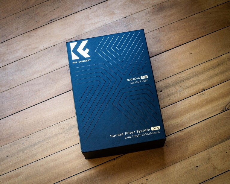 Blue product packaging box with geometric arrow pattern on wooden floor.