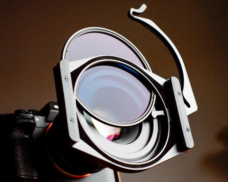 Collapsible lens filters or diffusers with white frames and adjustment handles stacked together.