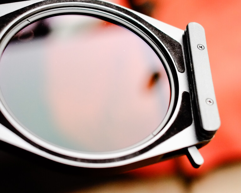 Close-up view through eyeglasses with blurred warm-toned background.