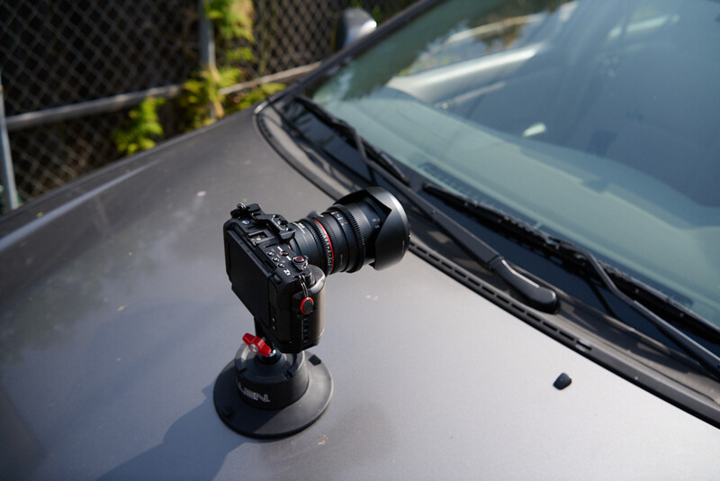 Camera mounted on vehicle hood with suction cup stabilizer in bright sunlight.