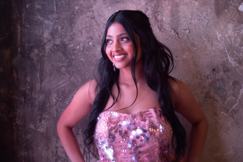 Model leaning on a wall, smiling