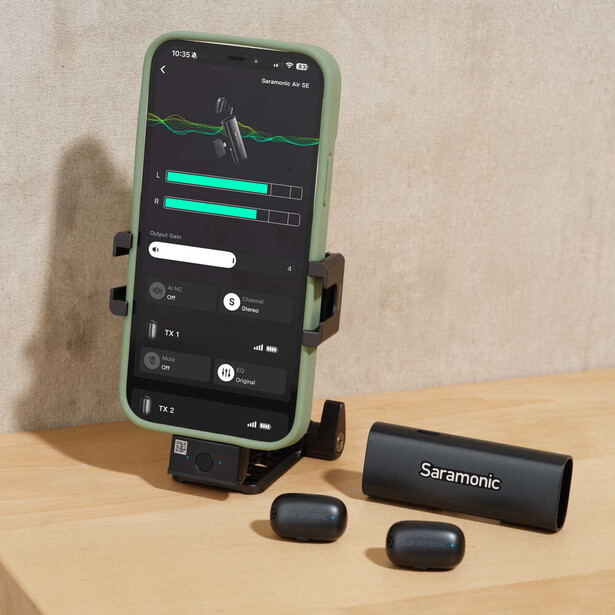 Smartphone mounted on a stand displaying audio waveforms and levels, with wireless microphone system components arranged in front.