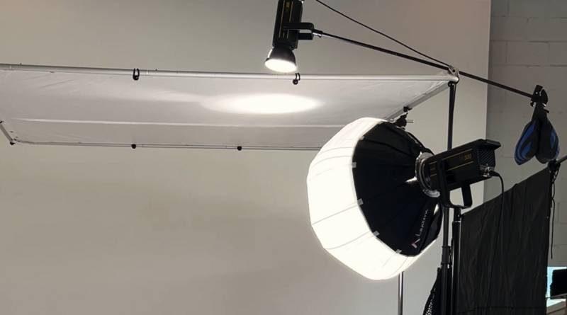 Professional studio lighting setup with large softbox and key light mounted on overhead rigging system.