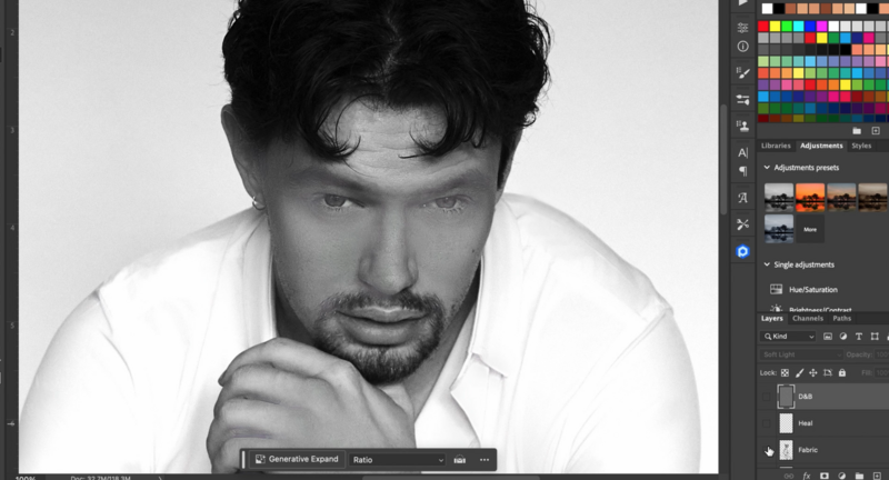 Black and white portrait of a man with dark hair and facial hair, resting his face on his hand in a contemplative pose while wearing a white shirt.