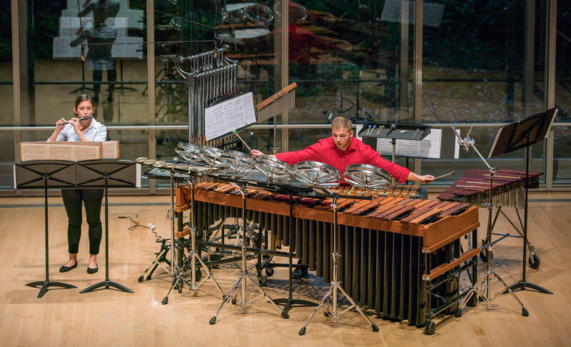 Two musicians performing in a concert hall, one playing keyboard and one playing vibraphone.