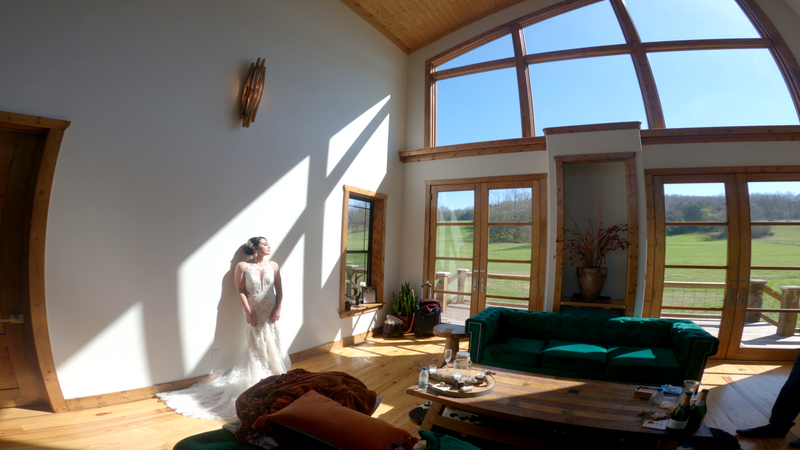 Woman in white dress standing in bright sunlight streaming through large windows in a modern interior space.