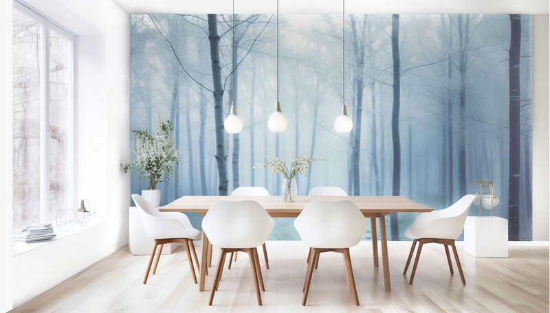 Modern dining room with white chairs around wooden table, forest mural backdrop, pendant lights.