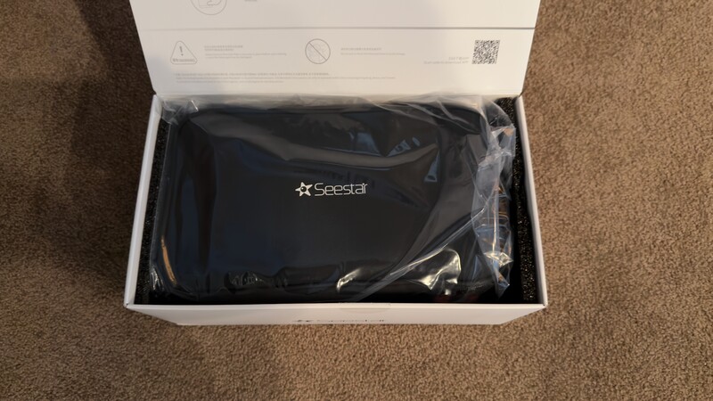 Black Seeda device in plastic packaging inside white retail box on carpet.