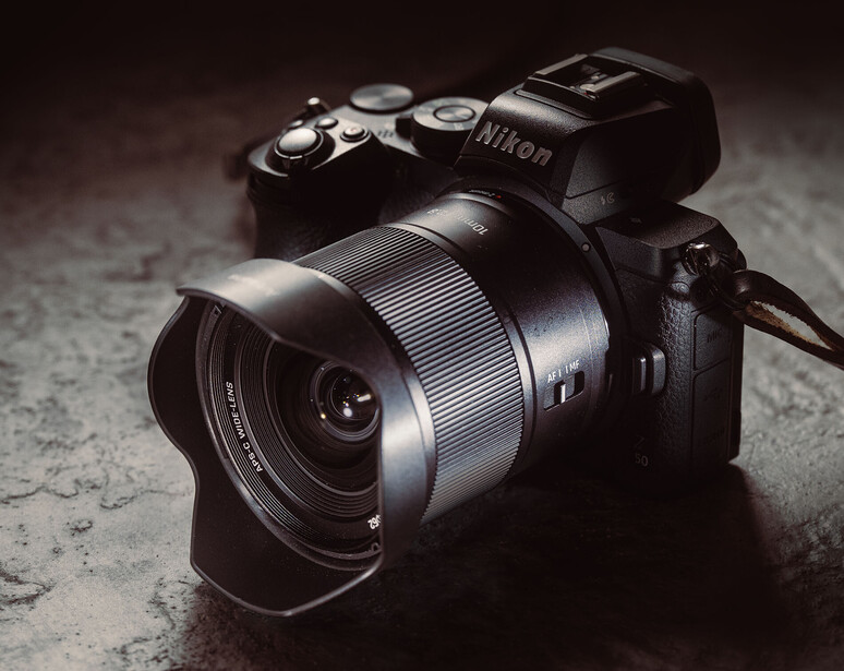 Nikon mirrorless camera with wide-angle lens on textured concrete surface.