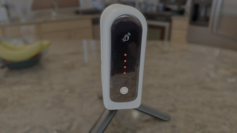White and gray desktop device with rounded top, dark display panel, and illuminated indicator lights.