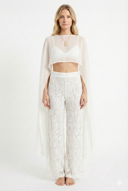 Woman in sheer white linen crop top and wide-leg pants standing barefoot against neutral background.