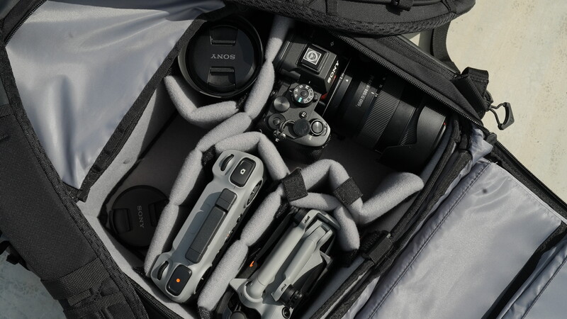 Photography equipment neatly organized in a camera bag, including a Sony camera body, lenses, and a watch.