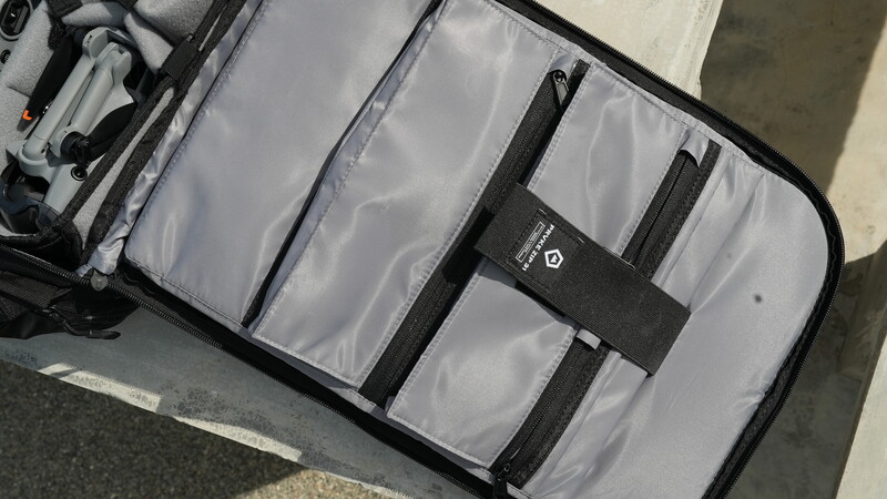 Open camera gear organizer case with clear compartments and black dividers containing photography equipment.