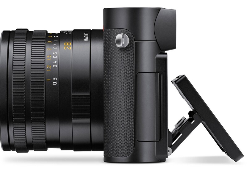 Black mirrorless camera with attached lens shown from the side profile with flip-out screen extended.