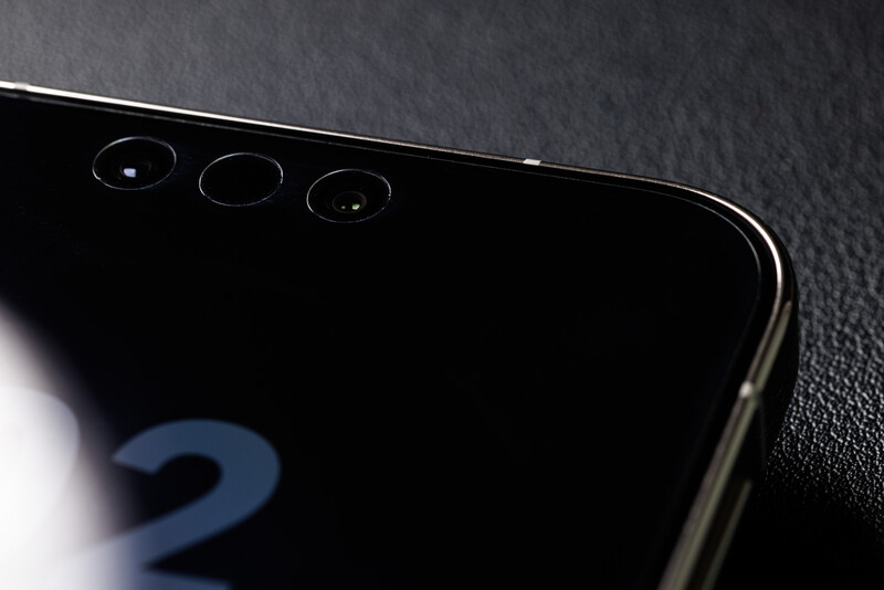 Close-up of a smartphone's triple rear camera array against a dark textured surface.