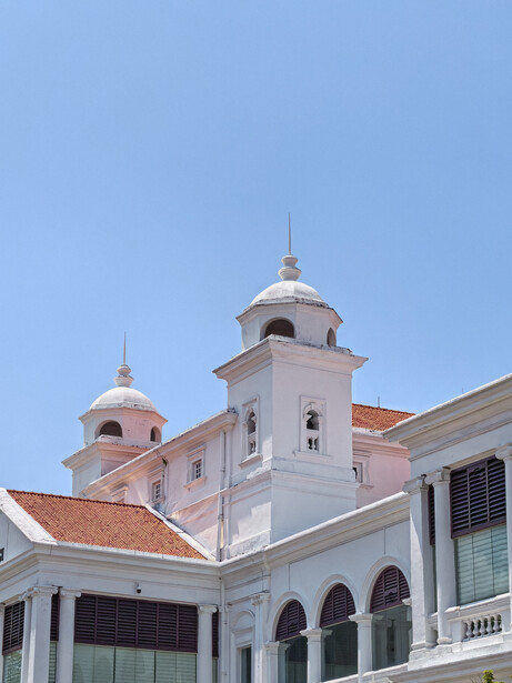 White colonial-style church with twin domed towers against clear blue sky.