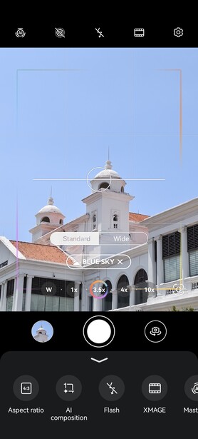 Colonial-style white building with two domed towers and terracotta roof tiles against clear blue sky.