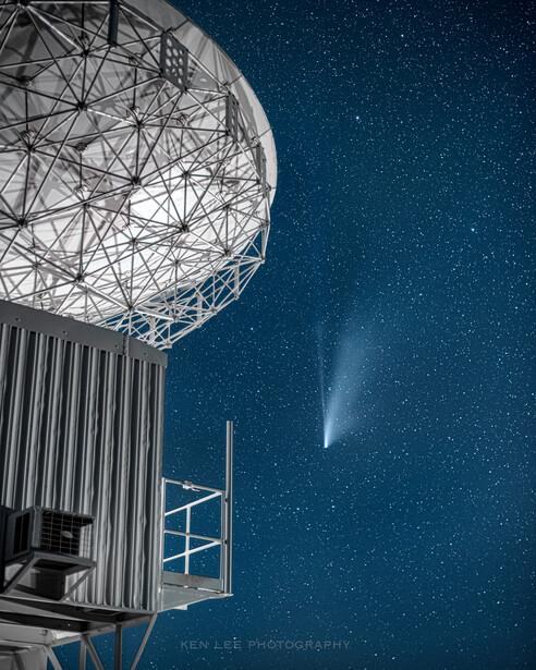 Radio telescope dome against starry night sky with comet visible in upper right.